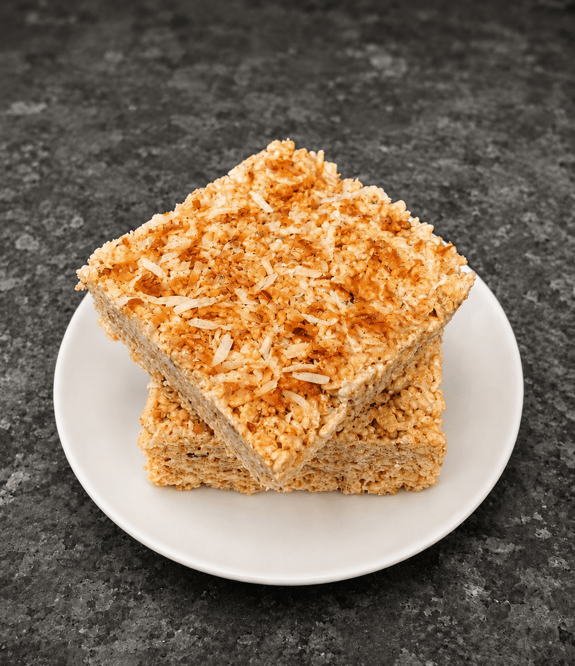 Stacked marshmallow crispy treats topped with toasted coconut