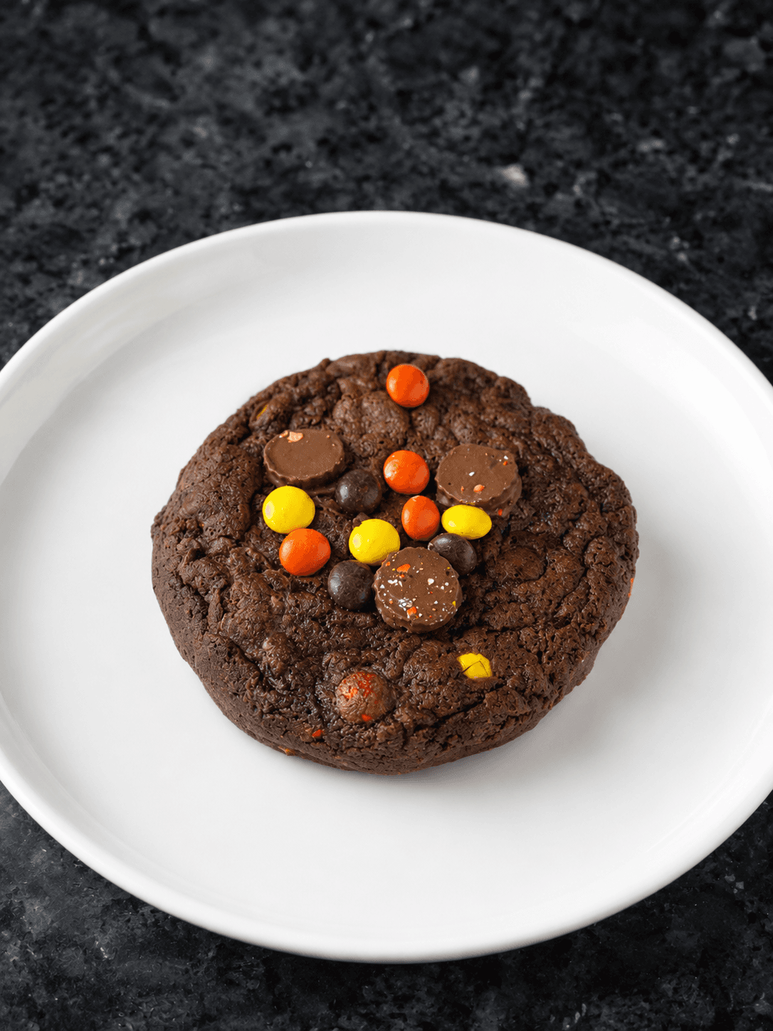 Chocolate cookie topped with peanut butter cups and colorful candy